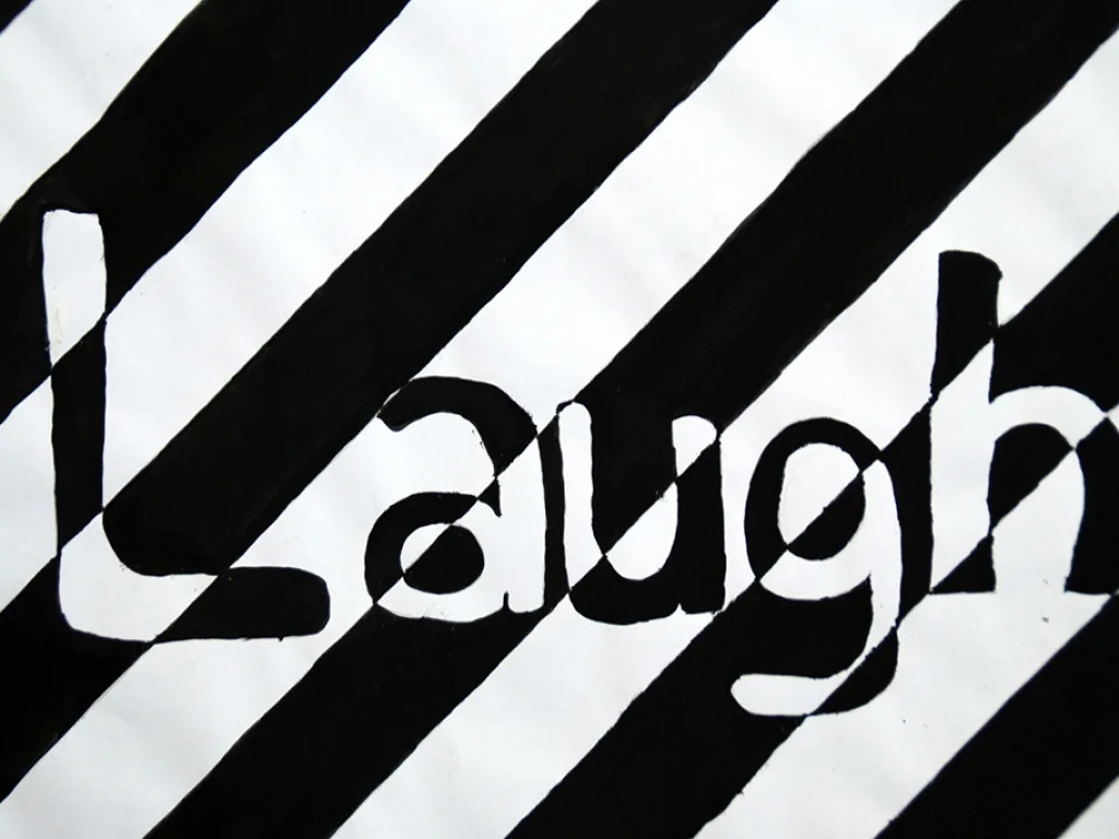 Der Schriftzug „Laugh“ als Scherenschnitt auf gestreiftem Grund.